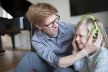 Sorridente padre e figlia con cuffie a casa — Foto stock