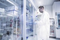 Científico abriendo refrigerador en laboratorio microbiológico - foto de stock