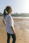 Спортивний молода жінка, стоячи на пляжі — стокове фото