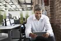Homme d'affaires au bureau regardant tablette numérique — Photo de stock