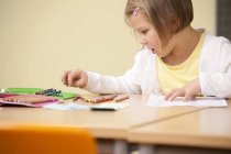 Studentessa alla scrivania della scuola con matite di colore — Foto stock
