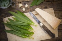 Ingredienti per la preparazione di pesto ramson, foglie e formaggio su tavola di legno con coltello — Foto stock