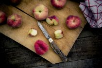 Целые и нарезанные персики на доске — стоковое фото