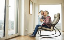 Mère et fille sur fauteuil à bascule partage écouteurs — Photo de stock