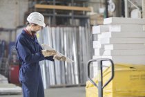 Almacenista en almacén mirando el material de construcción - foto de stock