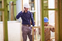 Construction worker and foreman measuring wood frame — Stock Photo
