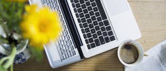 Cup of coffee, flowers, newspaper and laptop on wood — Stock Photo