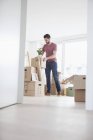 Young man in new flat unpacking cardboard boxes — Stock Photo