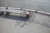 Bicycle leaning at bench against water on background — Stock Photo