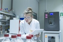 Biólogo en laboratorio examinando soluciones en frascos - foto de stock