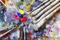 Paintbrushes and fresh paint on artist's palette — Stock Photo