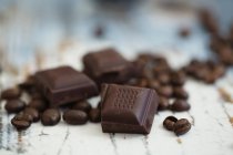 Жареный кофе в зернах и кусочки темного шоколада на дереве — стоковое фото