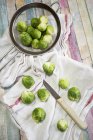 Brussel sprout in colander, kitchen towel and knife — Stock Photo