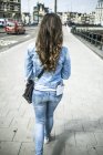 Niederlande, amsterdam, Rückansicht einer Touristin, die auf dem Bürgersteig geht — Stockfoto