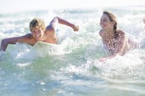 Happy young couple lying on surfboards in the sea — Stock Photo