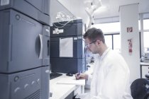 Científico en laboratorio microbiológico escribiendo un registro - foto de stock