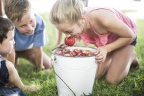 Menina tentando tirar maçã do balde com água — Fotografia de Stock