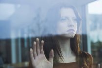 Serious young woman behind windowpane — Stock Photo