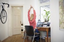 Жінка, сидячи за столом у її workroom розтягування — стокове фото