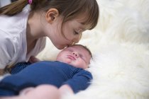 Menina beijando irmão recém-nascido — Fotografia de Stock