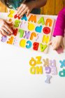 Mani di ragazze con puzzle alfabeto di legno — Foto stock