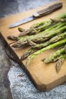 Organic green asparagus on chopping board — Stock Photo