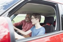 Padre che insegna al figlio a guidare un'auto, vista laterale — Foto stock