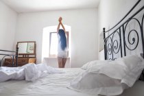 Joven atractiva mujer en estiramiento en el dormitorio - foto de stock
