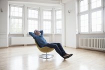 Relaxado homem sentado em poltrona em apartamento vazio — Fotografia de Stock