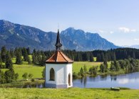 Germania, Baviera, Allgaeu, Cappella a Hegratsried lago con alberi sulla riva — Foto stock