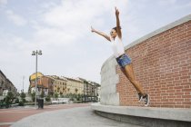 Mujer joven saltando por la estructura construida con los brazos extendidos - foto de stock