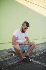 Homem sentado no skate e mensagens de texto — Fotografia de Stock