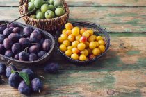 Baskets of plums, mirabelles and greengages on wood — Stock Photo