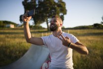 Homem tomando selfie enquanto mostra sinal de vitória — Fotografia de Stock