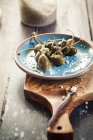 Framboesas em conserva, Capparis spinosa, com sal marinho no prato, tiro estúdio — Fotografia de Stock