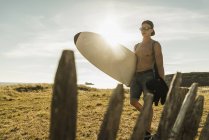 Jovem carregando prancha na costa — Fotografia de Stock