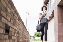 Femme d'affaires avec des documents et du café pour aller marcher dans la rue — Photo de stock