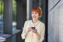 Smiling young woman outdoors with cell phone — Stock Photo