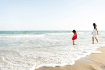 Bambina e sua madre a piedi sul lungomare sulla spiaggia — Foto stock