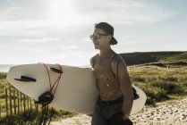 Jovem carregando prancha na costa — Fotografia de Stock