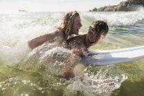 Подростковая пара веселится на доске для серфинга в море — стоковое фото