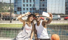 Молодая пара делает селфи на баскетбольной площадке — стоковое фото