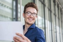 Ritratto di giovane uomo d'affari sorridente con tablet digitale — Foto stock
