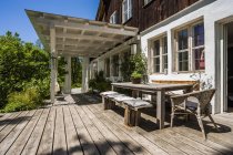Деревянная терраса со столом и скамейками в солнечном свете — стоковое фото