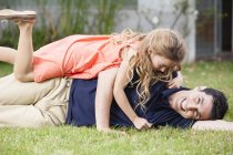 Brincalhão pai e filha deitado na grama — Fotografia de Stock