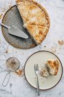 Яблучний пиріг з вершками та корицею зі скибочкою на тарілці на білому мармурі — стокове фото