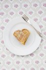 Dish of heart shaped waffles sprinkled with icing sugar on patterned cloth — Stock Photo