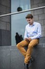 Portrait of sitting young man using his smartphone — Stock Photo