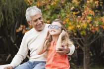 Дедушка и счастливая внучка в солнечных очках на улице — стоковое фото