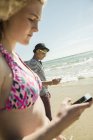 Adolescente coppia a piedi sul lungomare della spiaggia utilizzando smartphone — Foto stock